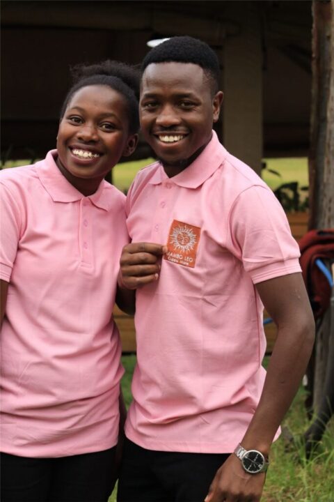 Two smiling members of the Mambo Leo team in branded pink polo shirts